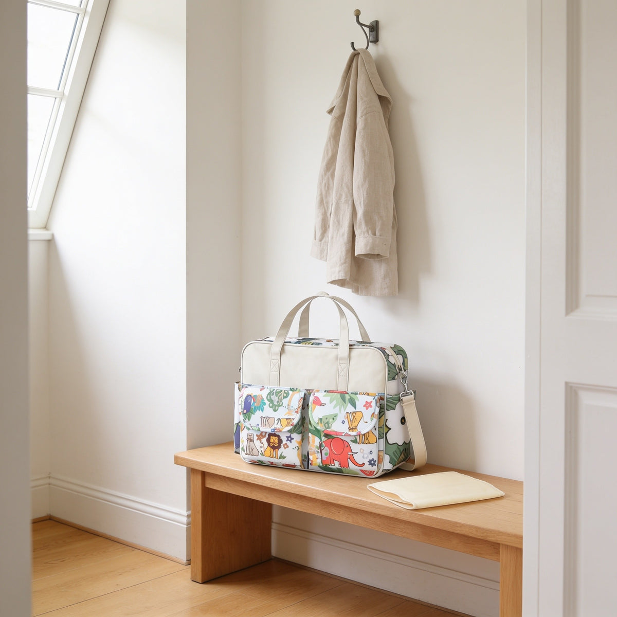 Safari animal print diaper tote bag on a light oak hallway bench, its changing mat folded beside it.