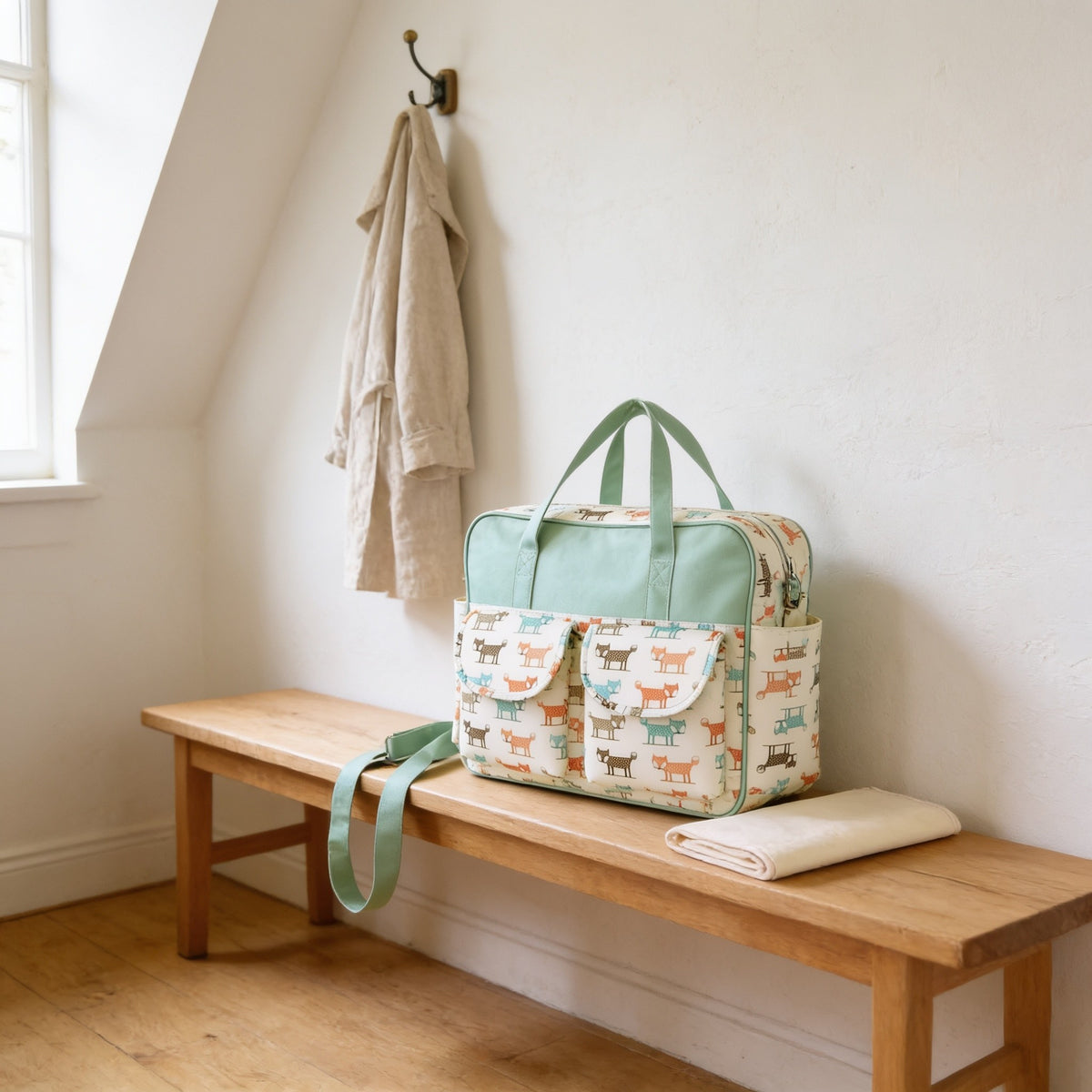 Fox print diaper tote bag on a light oak hallway bench, its changing mat folded beside it.