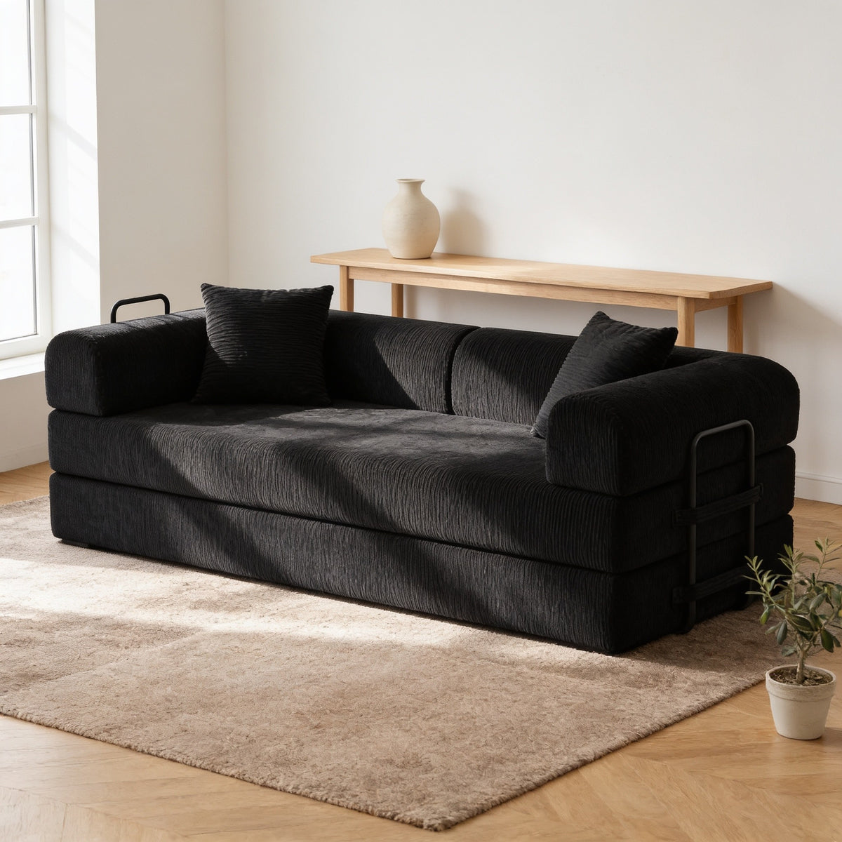 Black corduroy convertible sofa bed in sofa mode in a warm living room.